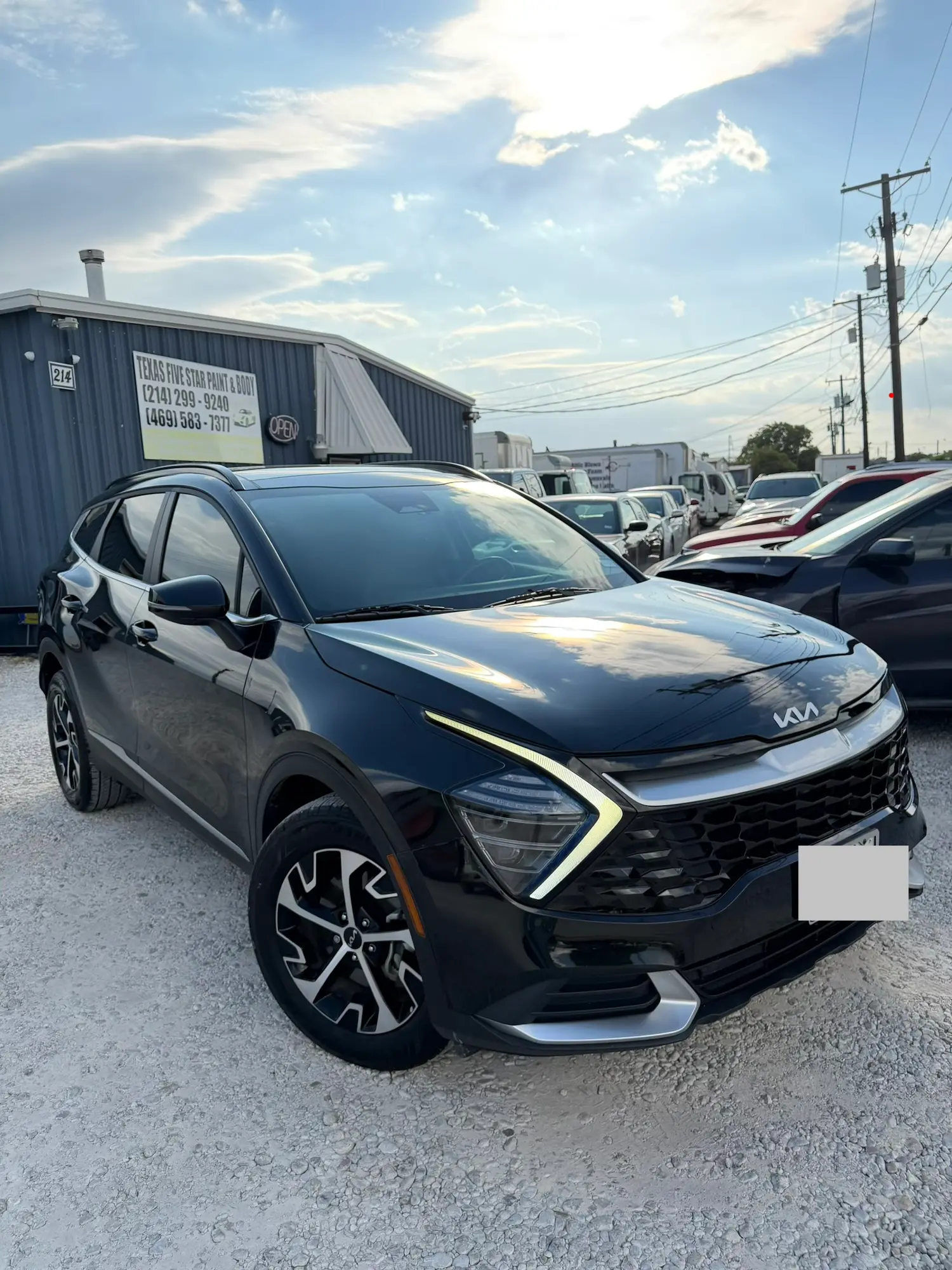Black Kia Sportage parked in front of the Texas Five Star Paint & Body shop