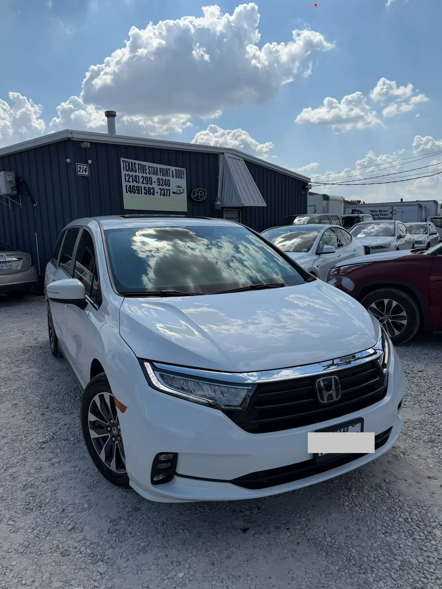 White Honda minivan parked on gravel in front of the Texas Five Star Paint & Body shop