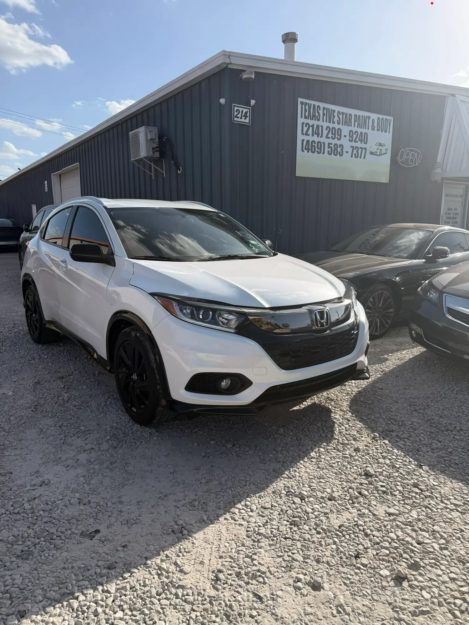 White Honda SUV parked on gravel in front of Texas Five Star Paint & Body shop