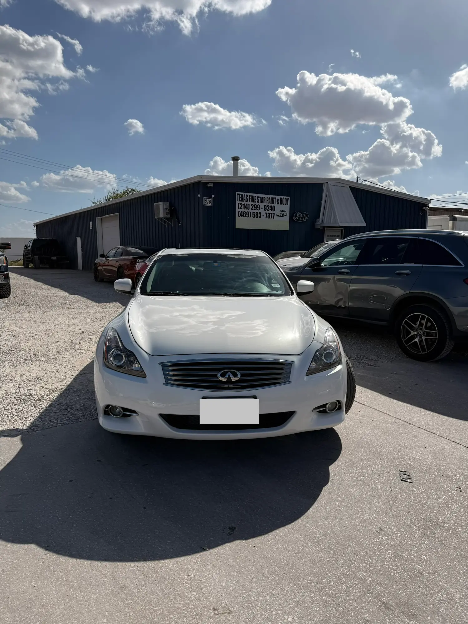 White Infiniti sedan parked in front of the Texas Five Star Paint & Body shop under a partly cloudy sky